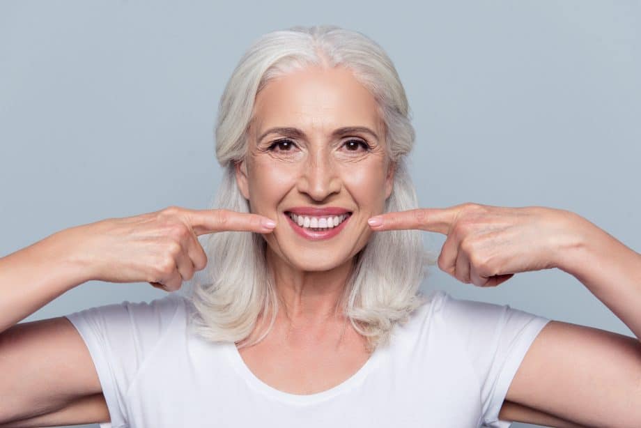 Woman showing off her dentures vs dental implants in Milwaukee WI